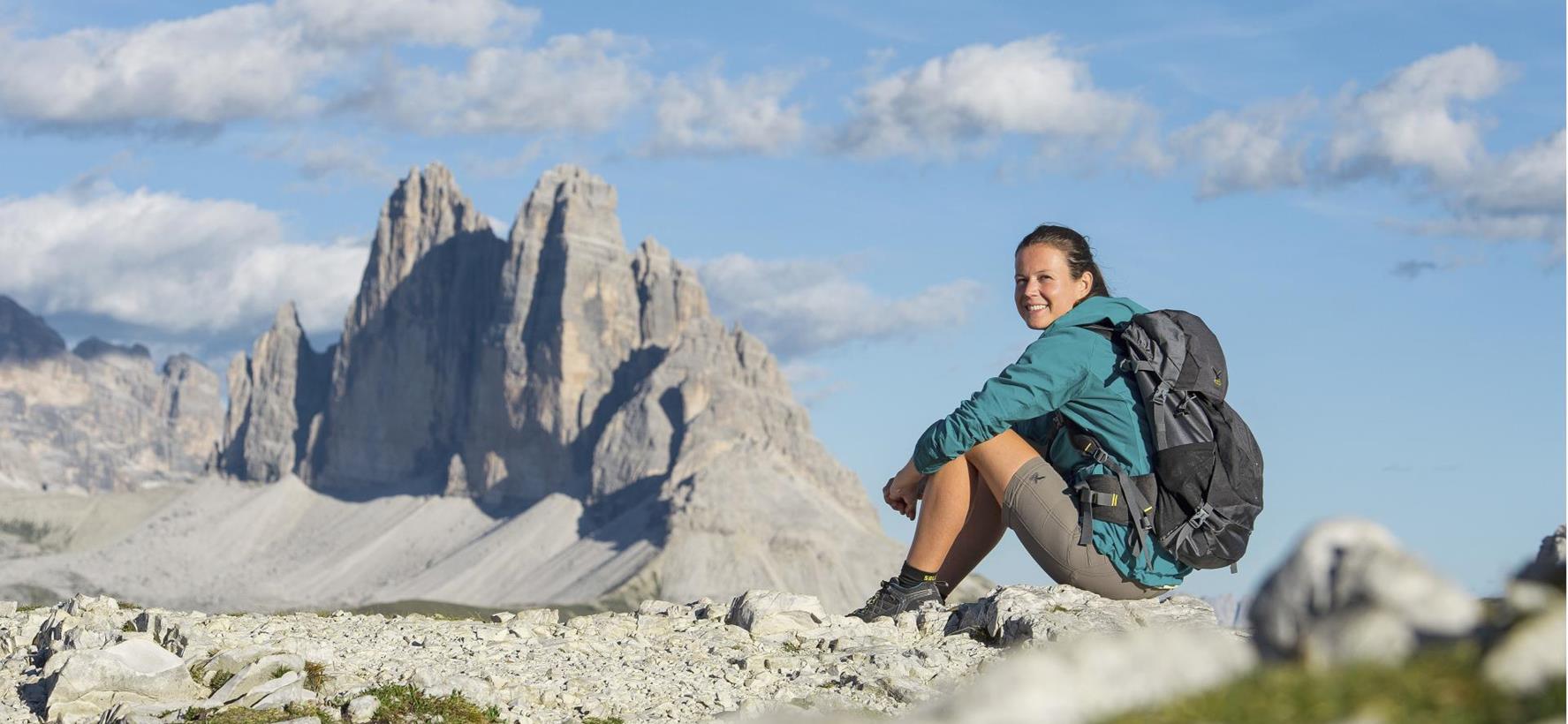 Hiker with a backpack in front of the Three Peaks in the Dolomites