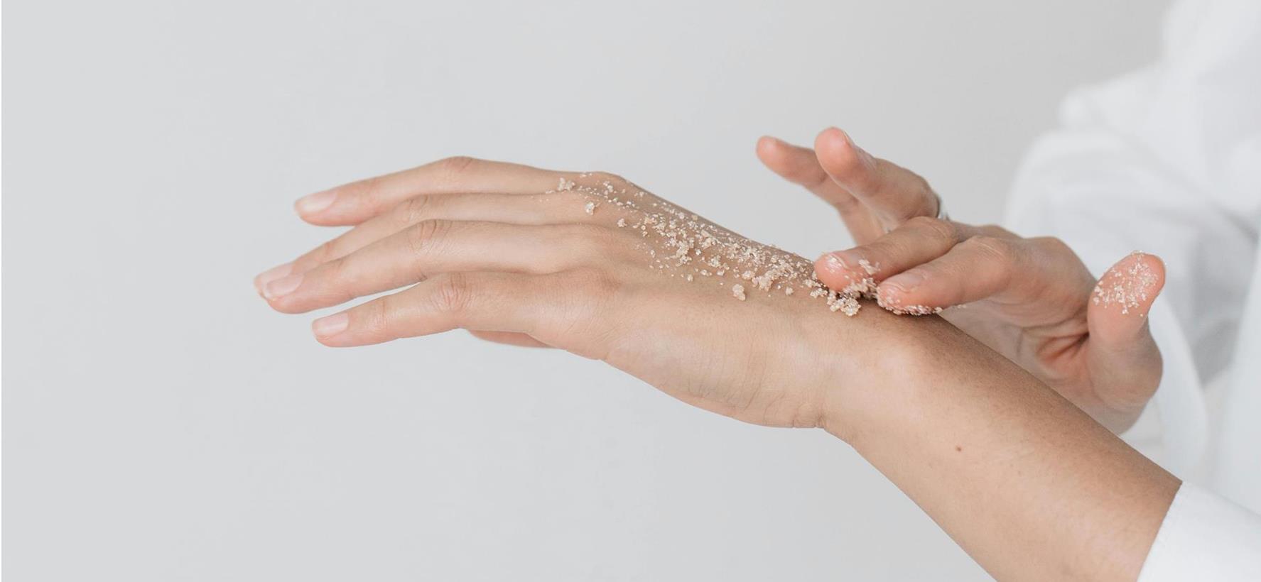 Primo piano di mani curate con crema per le mani applicata.