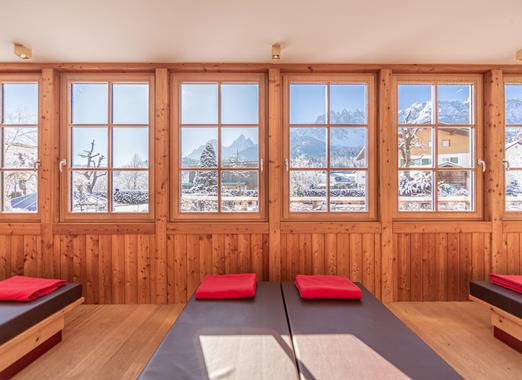 Ruheraum mit Liegen, Holzwänden und Panoramafenstern mit Blick auf die Berglandschaft.