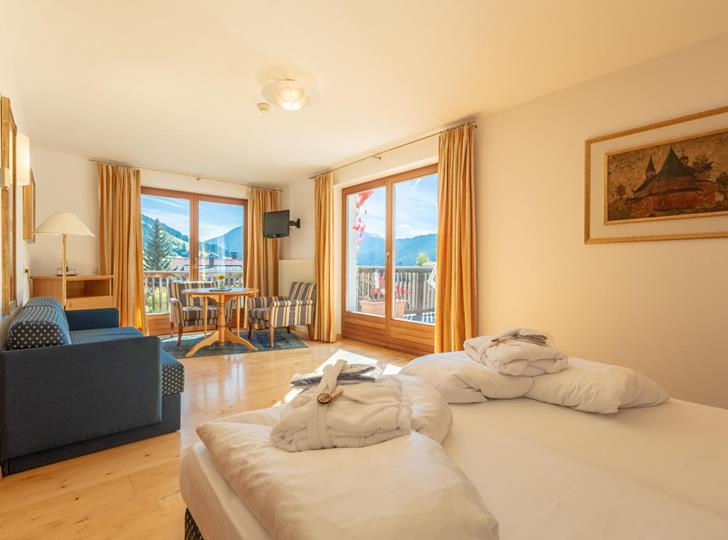 Junior Suite with double bed, seating area and large windows overlooking the greenery.