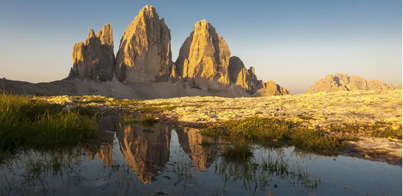 Le maestose Tre Cime di Lavaredo nelle Dolomiti in un paesaggio alpino sotto la luce del sole.