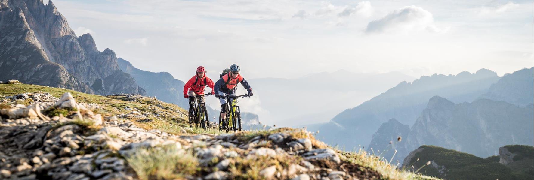 Due mountain biker su un sentiero attraverso il paesaggio estivo delle Dolomiti
