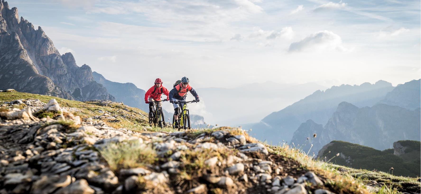 Due mountain biker su un sentiero attraverso il paesaggio estivo delle Dolomiti