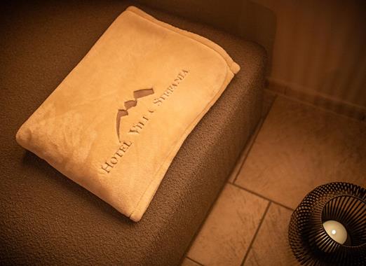 Beige Decke im Ruheraum mit dem aufgestickten Logo vom Hotel Villa Stefania.