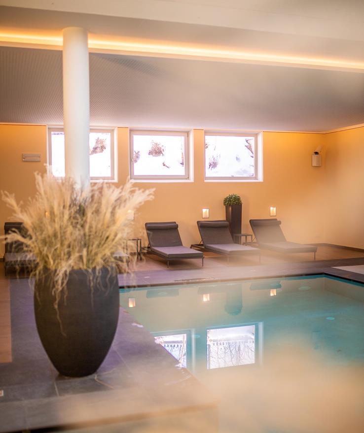 Hell und modern gestalteter Indoorpool mit bequemen Liegen.