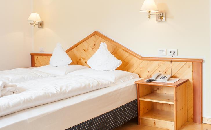 Camera Superior con letto matrimoniale, rivestimento in legno e comodino.