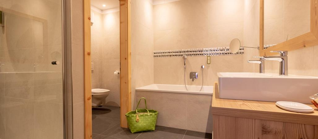 Badezimmer mit Badewanne, begehbarer Dusche, Waschbecken und großem Spiegel.