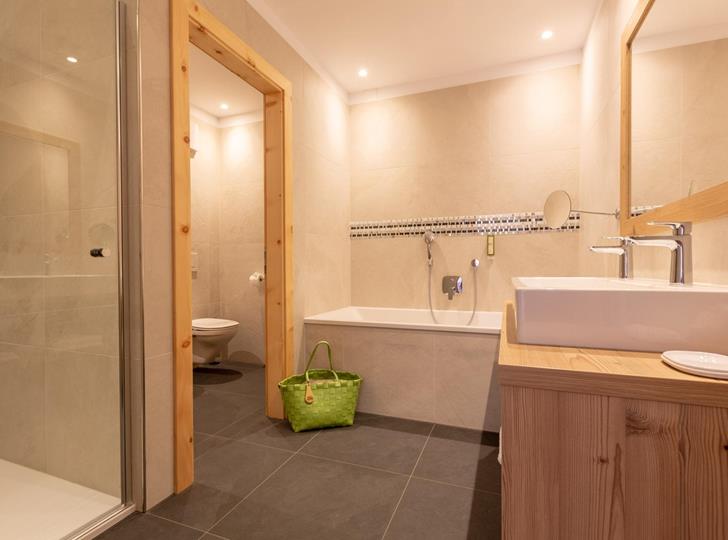 Badezimmer mit Badewanne, begehbarer Dusche, Waschbecken und großem Spiegel.