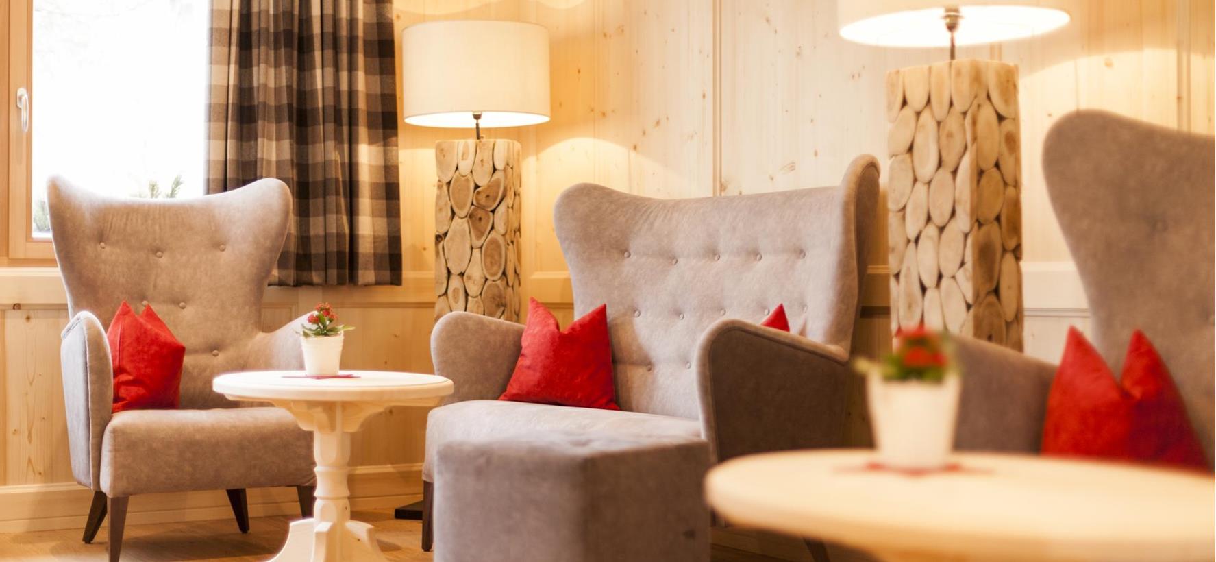Traditional lounge at Villa Stefania with light wood panelling, small round tables and cosy wingback armchairs.
