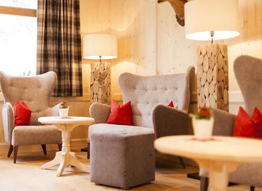 Traditional lounge at Villa Stefania with light wood panelling, small round tables and cosy wingback armchairs.