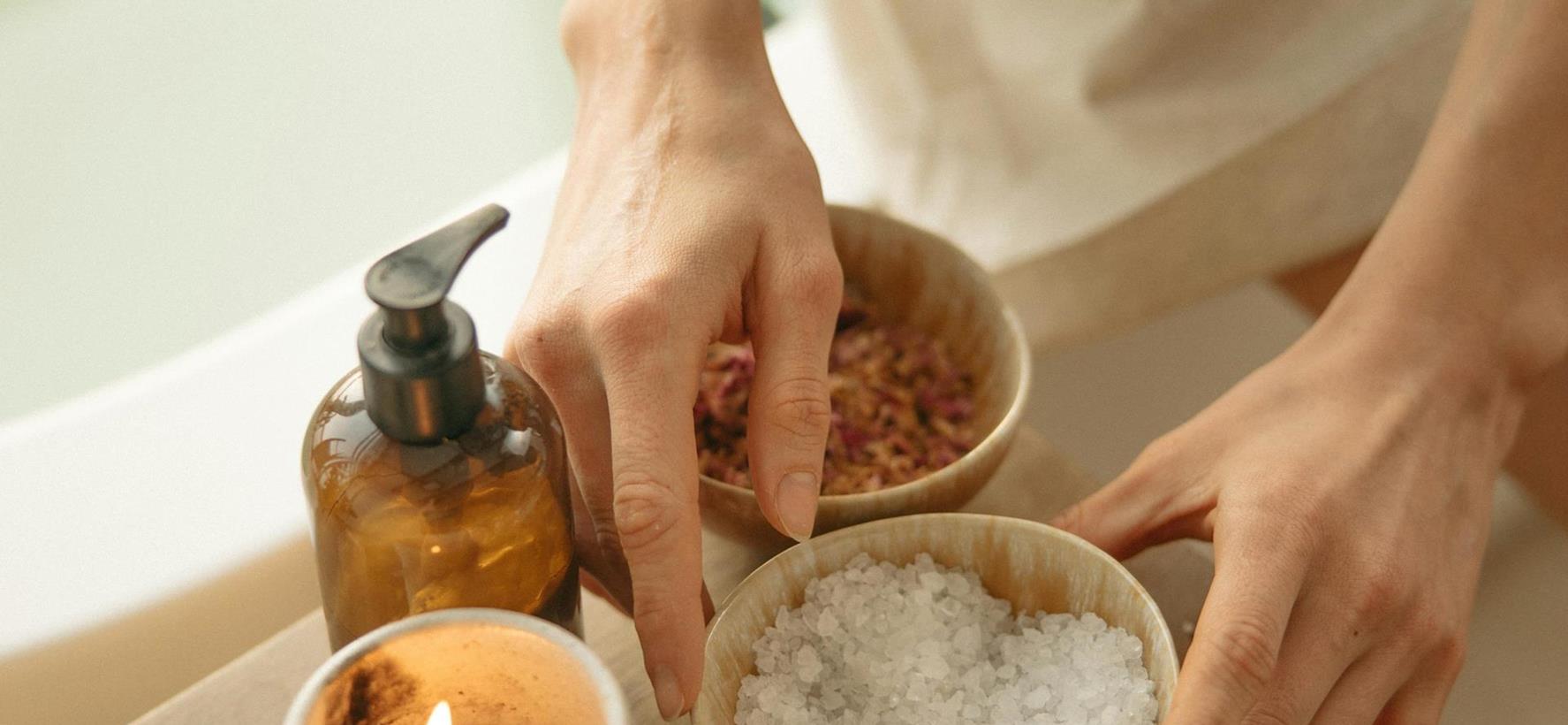 Preparazione di uno scrub benessere con ciotola, sale e candela su un tavolino.