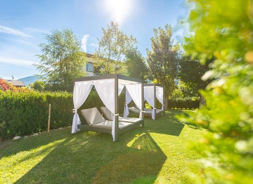 Garten der Villa Stefania mit großen Sonnenliegen umgeben von Bäumen.