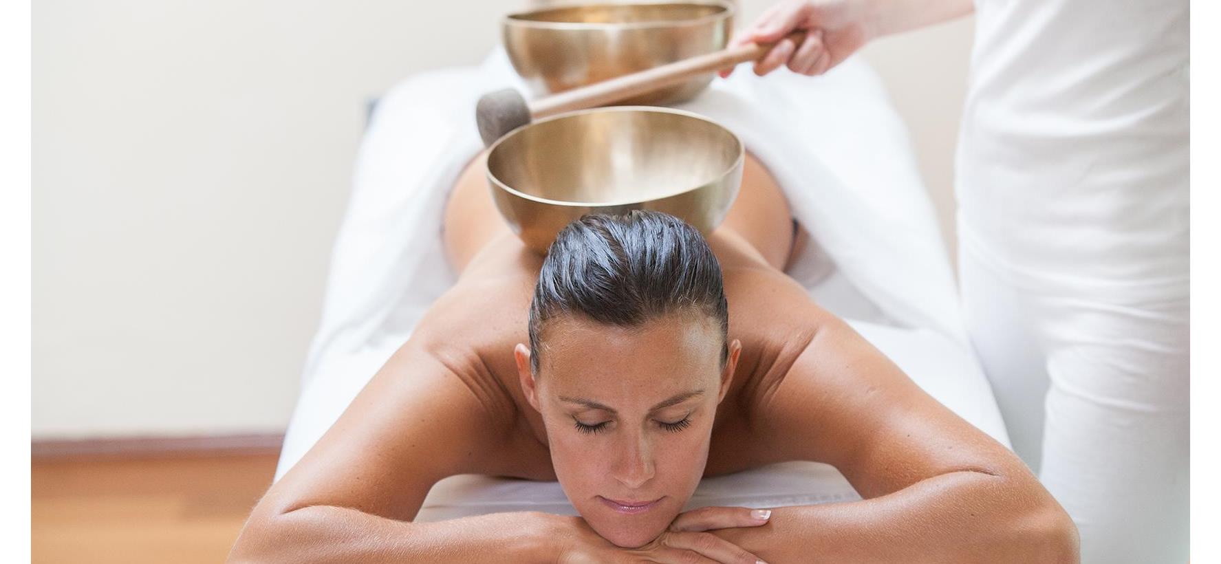 Donna durante un rilassante trattamento wellness con campane tibetane sulla schiena.