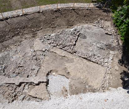 Nahaufnahme einer historischen Steinplatte mit fossilen Strukturen und natürlichen Gesteinsformationen.