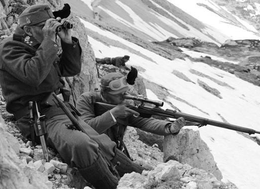 Historische Schwarz-Weiß-Aufnahme von Soldaten im Ersten Weltkrieg in einer verschneiten Berglandschaft der Dolomiten.