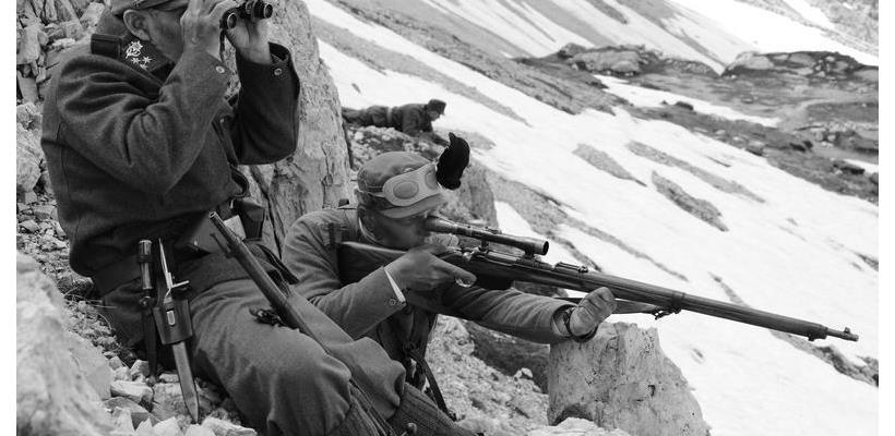Historische Schwarz-Weiß-Aufnahme von Soldaten im Ersten Weltkrieg in einer verschneiten Berglandschaft der Dolomiten.
