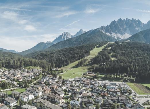 Aerial view of San Candido with meadows, forests and mountains in the background.