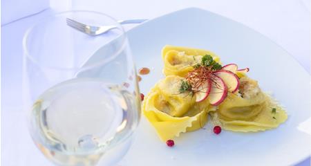 Tortellini on a white plate with melted butter, Parmesan cheese and fresh herbs.