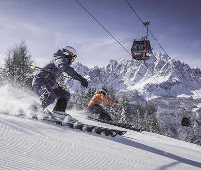 Skier on a ski slope in the snow-covered Dolomites, with striking mountain peaks in the background.