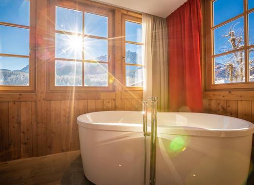 Freestanding bathtub in the Romantic Suite with panoramic window and views of the Dolomites.