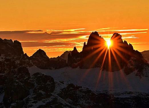 Tramonto sul Picco di Vallandro nelle Dolomiti con imponenti formazioni rocciose e calde tonalità arancioni della luce serale.