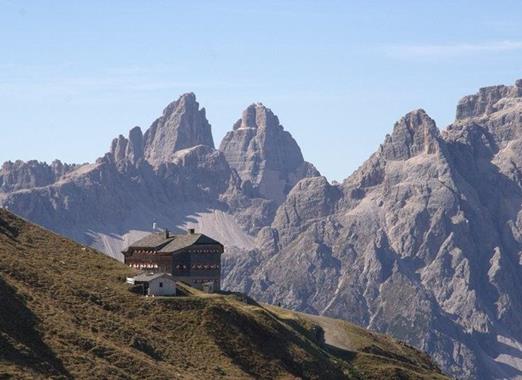 Blick auf die Sillianerhütte inmitten von Almwiesen mit markantem Dolomitengebirge im Hintergrund.