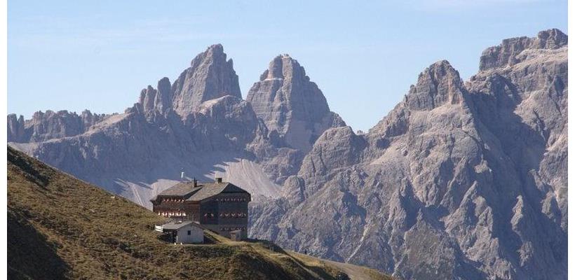 Blick auf die Sillianerhütte inmitten von Almwiesen mit markantem Dolomitengebirge im Hintergrund.