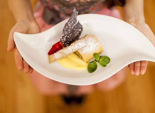 Strudel di mele su un piatto bianco con salsa alla vaniglia.