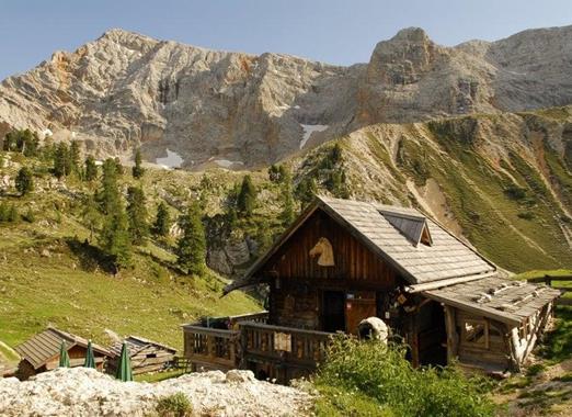 Rossalm nelle Dolomiti, circondata da verdi prati alpini e imponenti cime montuose.