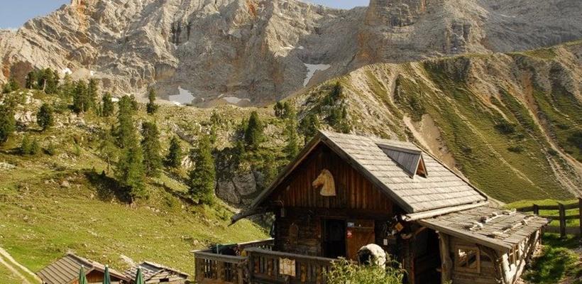 Rossalm in den Dolomiten, umgeben von grünen Almwiesen und markanten Berggipfeln.