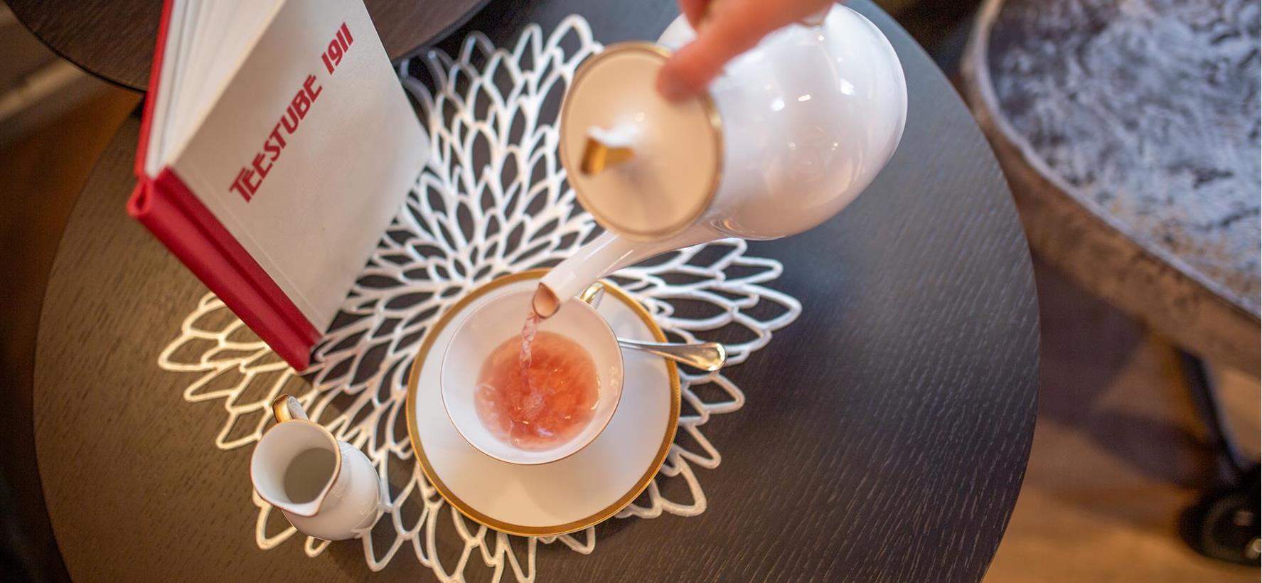 Tasse Tee auf einem kleinen Tisch mit Teekarte.