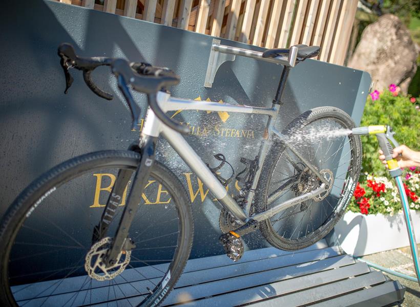 Close-up of a bicycle being hosed down with a garden hose.