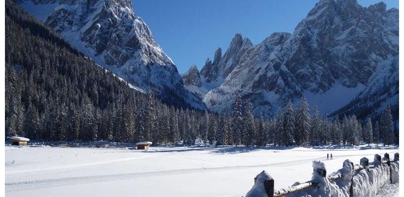Val Fiscalina innevata con bosco di conifere e le caratteristiche cime dolomitiche sullo sfondo.