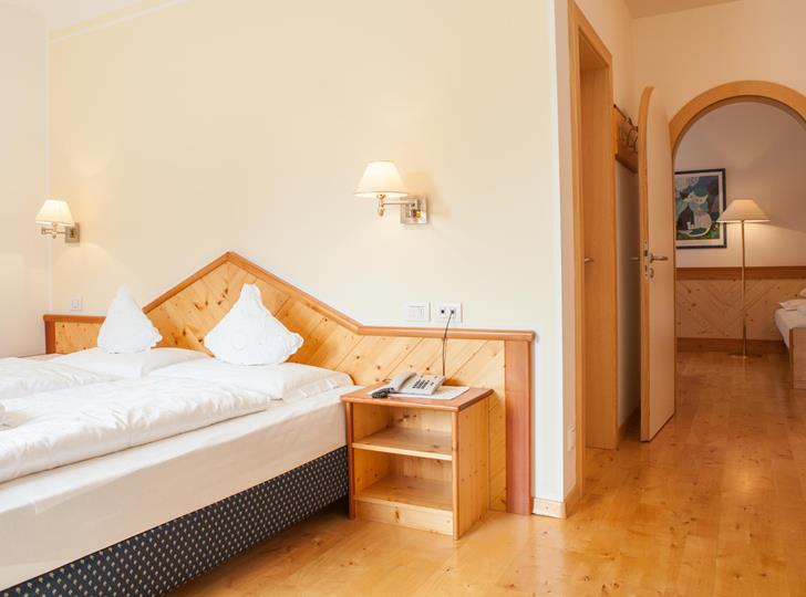 Family Suite con letto matrimoniale, pavimento in legno e passaggio ad arco.