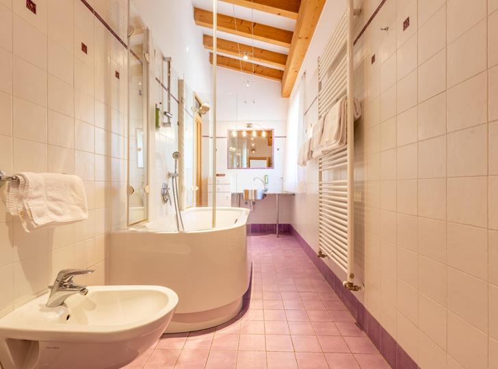Helles Badezimmer mit Badewanne, Waschbecken und Holzelementen.