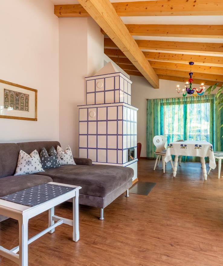 Soggiorno della Suite Panorama con divano grigio, tavolino bianco, soffitto con travi in legno e piante rampicanti davanti alla zona pranzo vicino alla finestra.
