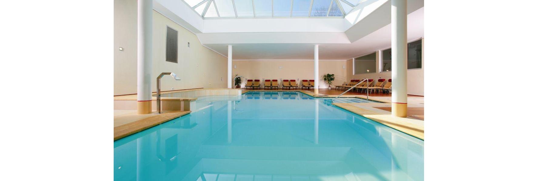 Piscina coperta dell’Hotel Villa Stefania con lettini e ampia vetrata sul tetto.
