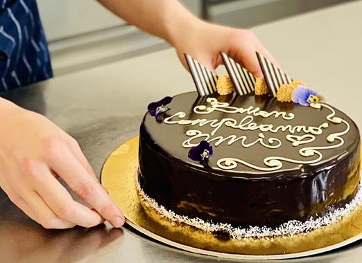 Nahaufnahme einer Schokoladentorte mit der Aufschrift Buon Compleanno.